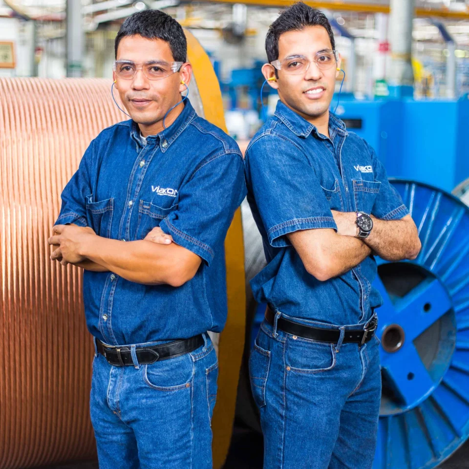 Retrato de dos colaboradores en planta; equipo humano y entorno industrial.